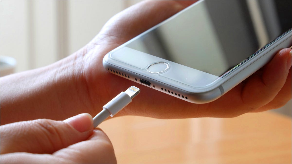 Una persona conectando un cable a un puerto Lightning de iPhone.