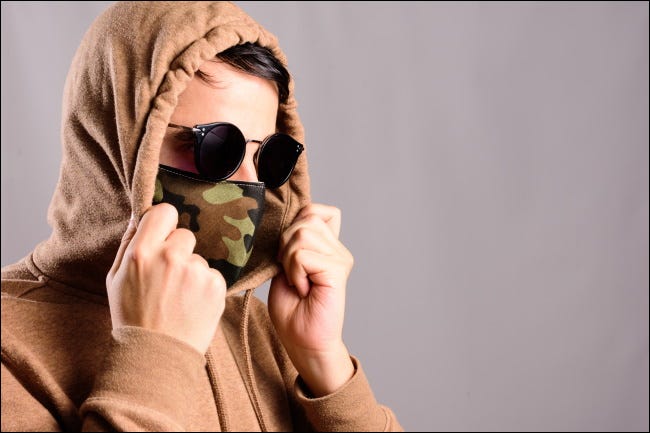 Una persona con mascarilla, sudadera con capucha y anteojos de sol.
