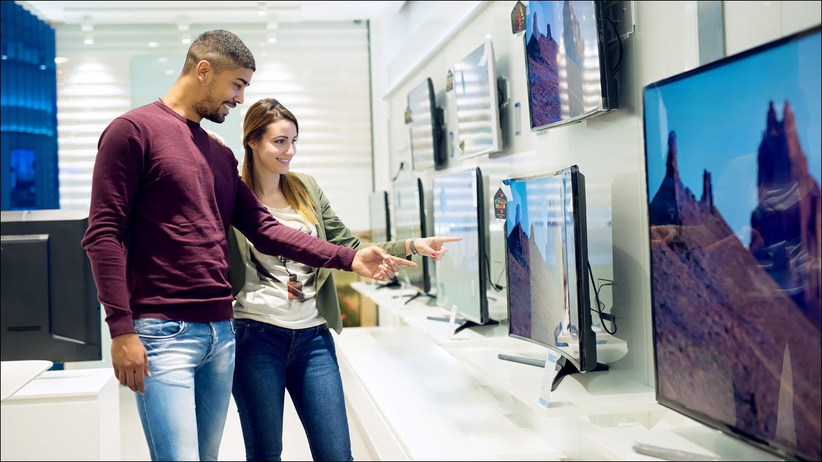 Dos personas comprando un televisor en una tienda de electrónica