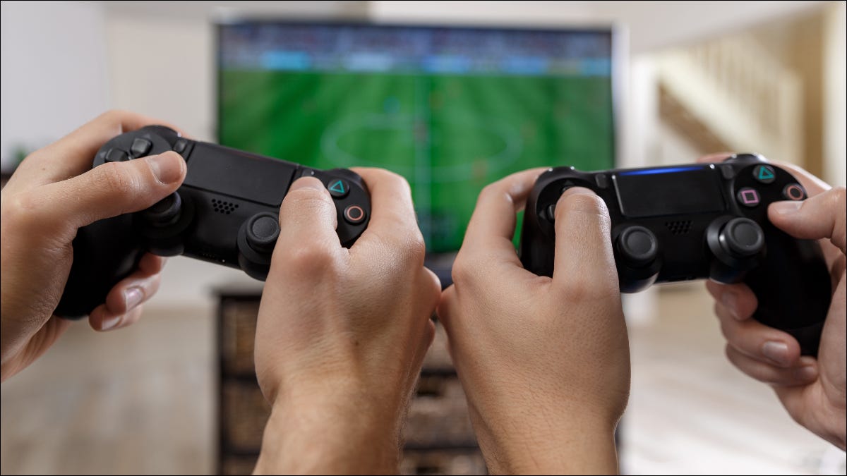 Dos personas sosteniendo controladores de Playstation y jugando un videojuego juntos
