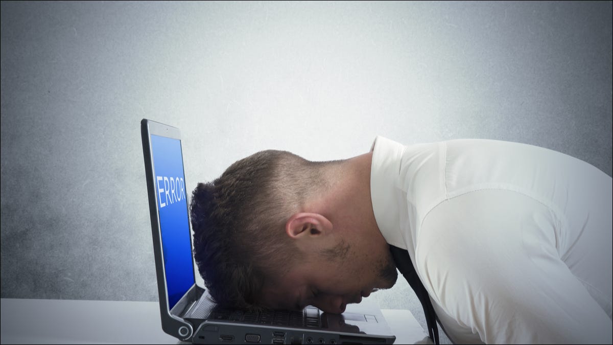 Un hombre descansando su cabeza en una computadora portátil con un error