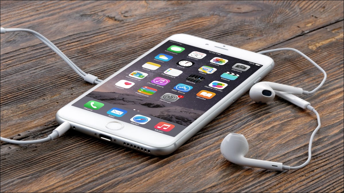 Un iPhone 6 Plus con auriculares conectados sobre una superficie de madera