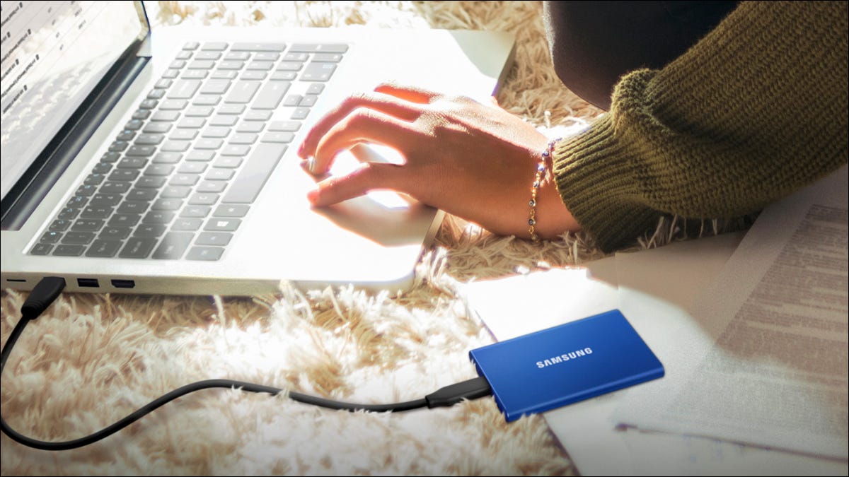 Un SSD externo de Samsung colocado en el suelo junto a un portátil