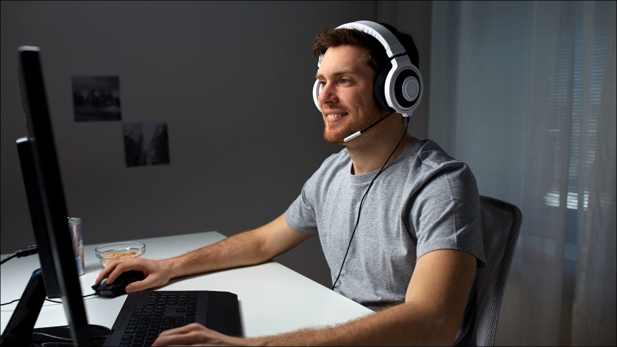 Jugador masculino sonriendo y usando una PC de escritorio.