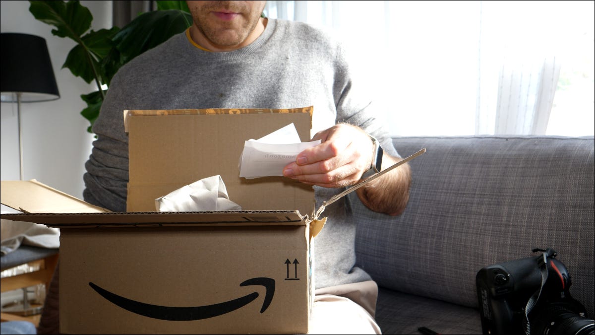 Hombre abriendo un paquete de Amazon y leyendo el comprobante de pedido.