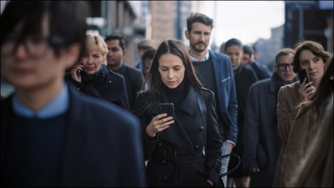 Una multitud de personas que usan teléfonos inteligentes en una calle de la ciudad.