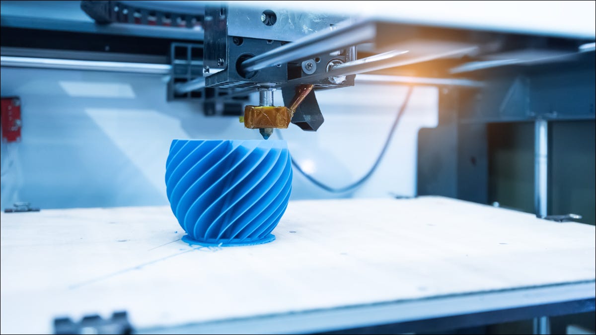 Una impresora 3D que crea un objeto azul en forma de espiral.