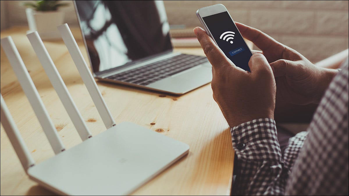 Una persona que conecta su teléfono inteligente al enrutador Wi-Fi de su hogar.