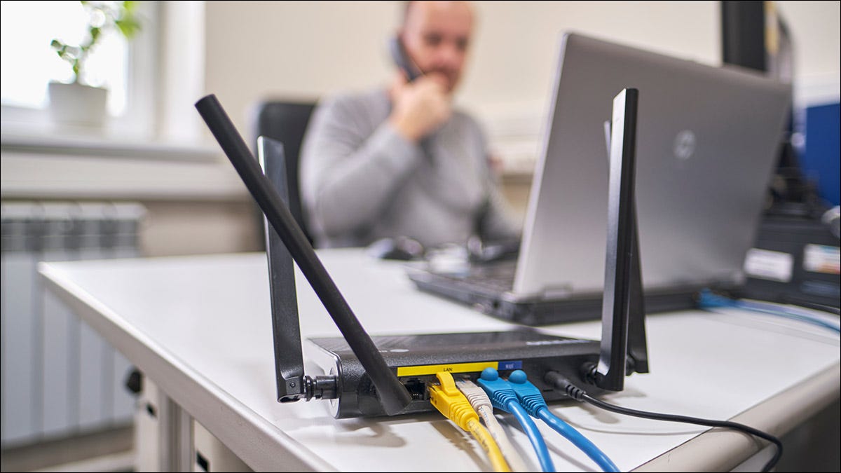 Una persona que trabaja en un escritorio con varios dispositivos conectados a un enrutador Wi-Fi.