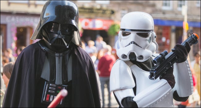 Dos personas disfrazadas de Darth Vader y un personaje de Stormtrooper de la franquicia Star Wars.