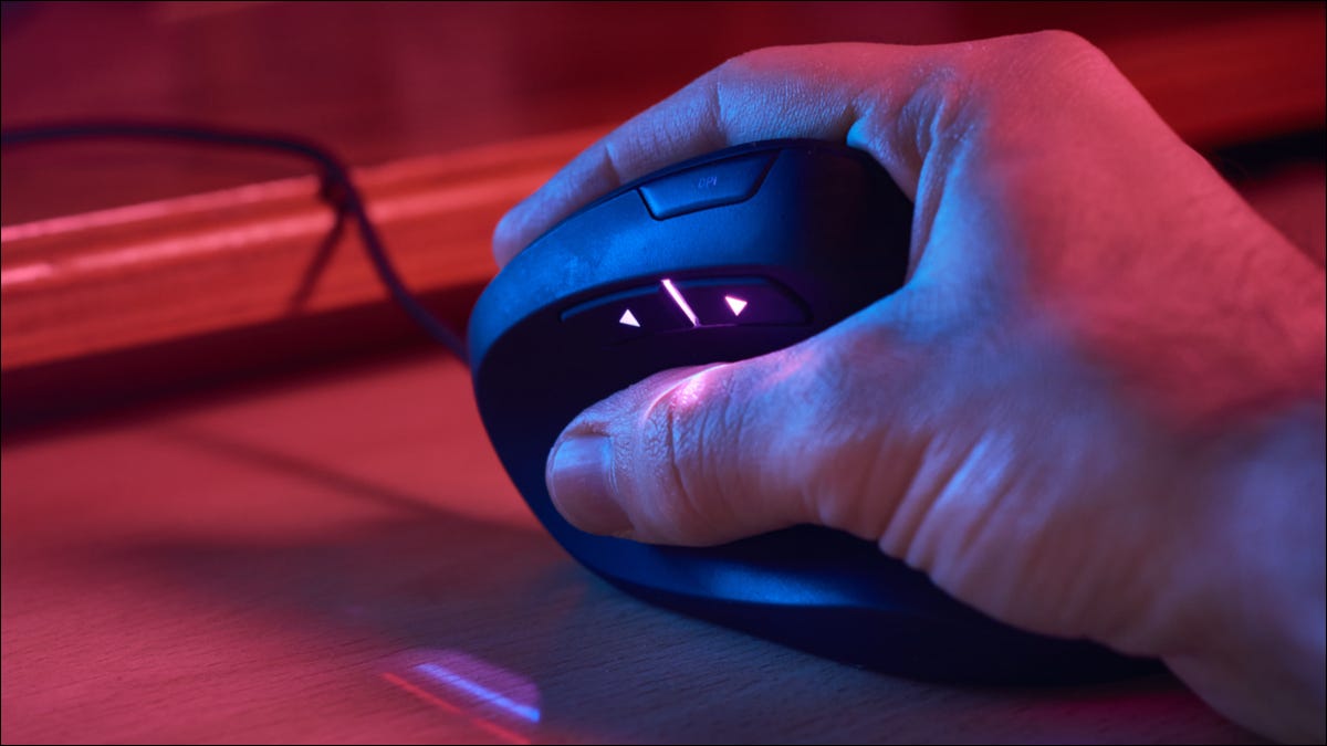 Primer plano de la mano de una persona en un mouse ergonómico con iluminación RGB.