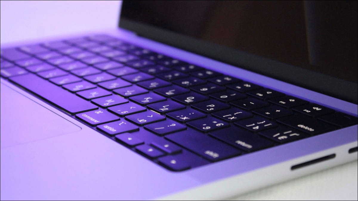 Primer plano de una MacBook Pro M1 con iluminación violeta.