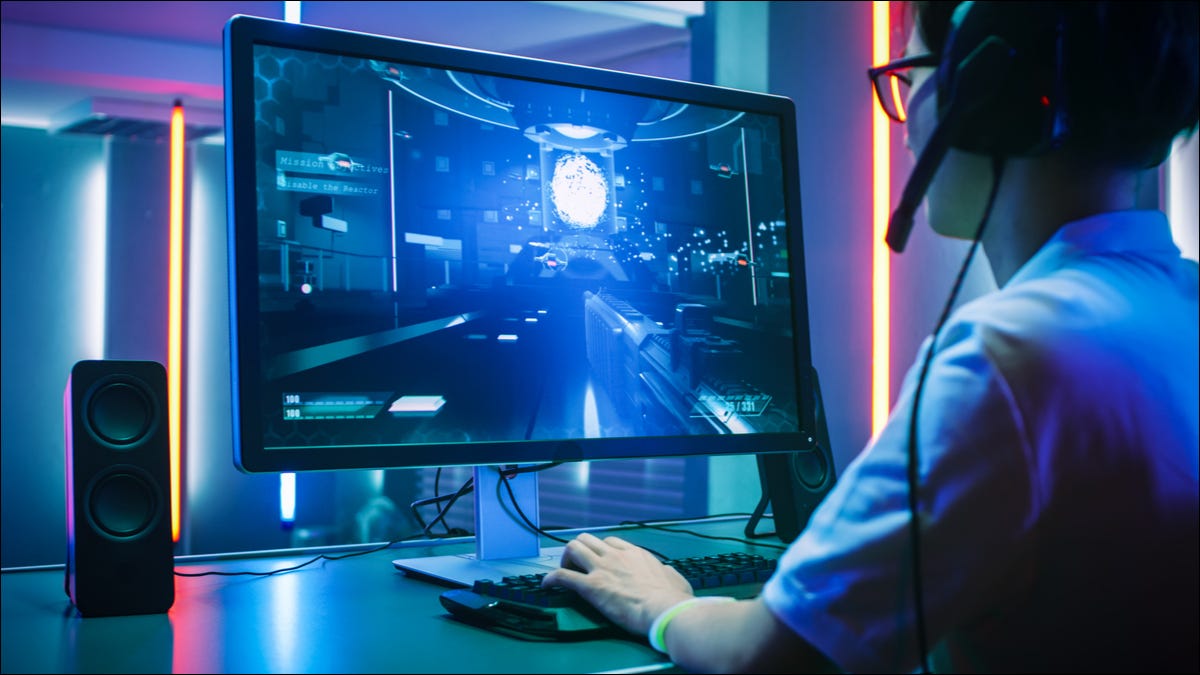 Vista posterior de un jugador profesional que usa un monitor de PC de gama alta.