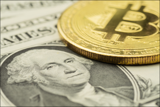 Una ficha de Bitcoin y un billete de un dólar.