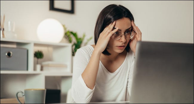 Mujer mirando una computadora portátil con una expresión estresada.