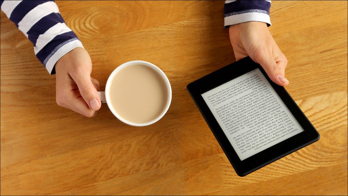 Persona leyendo Kindle mientras bebe café.