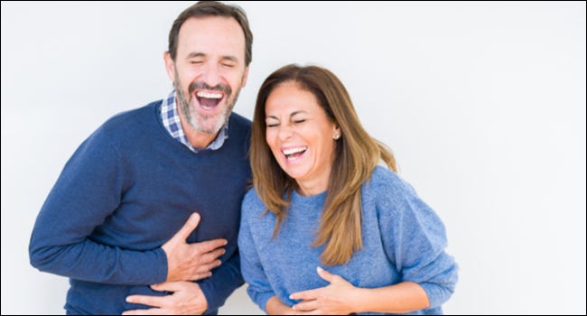 Una pareja agarrándose la barriga de la risa.