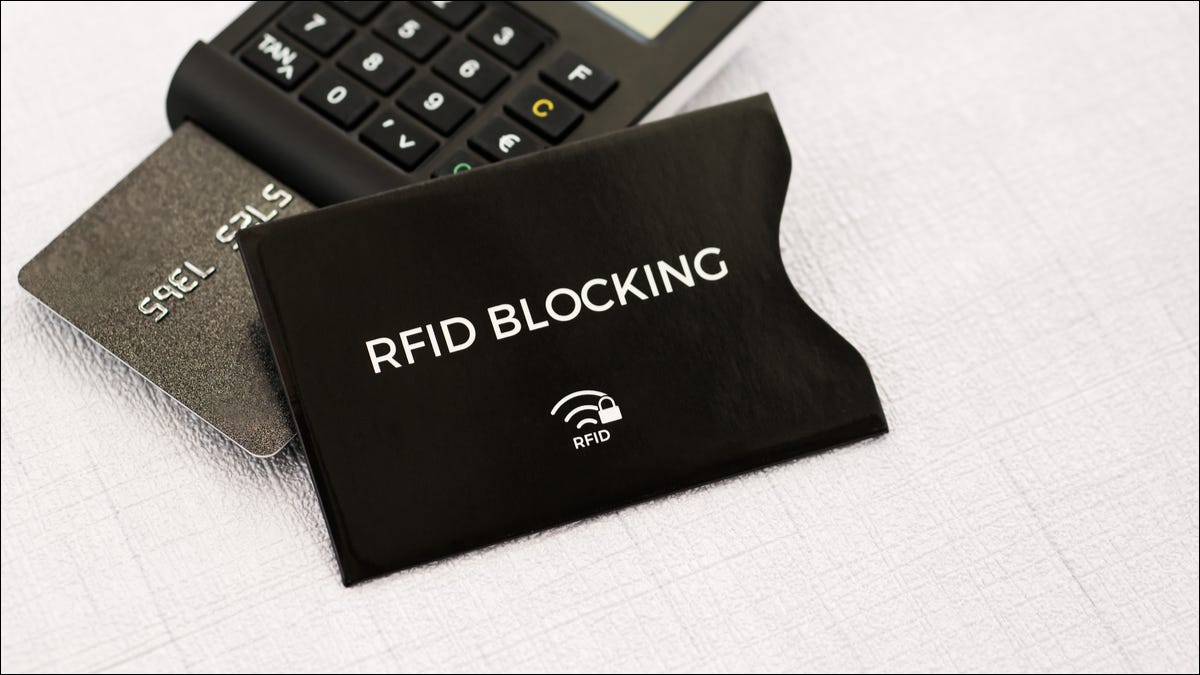 Una funda de bloqueo de RFID con una tarjeta de crédito en un lector de tarjetas detrás.