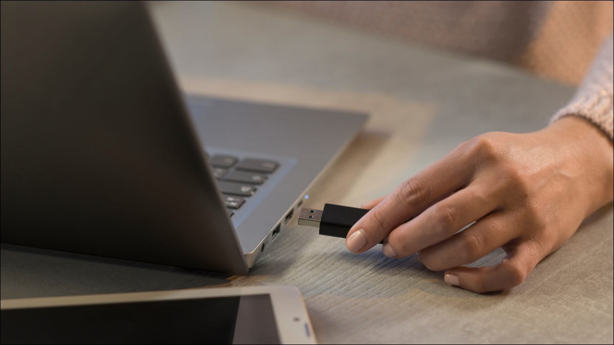 Mano de mujer conectando una unidad USB a una Macbook